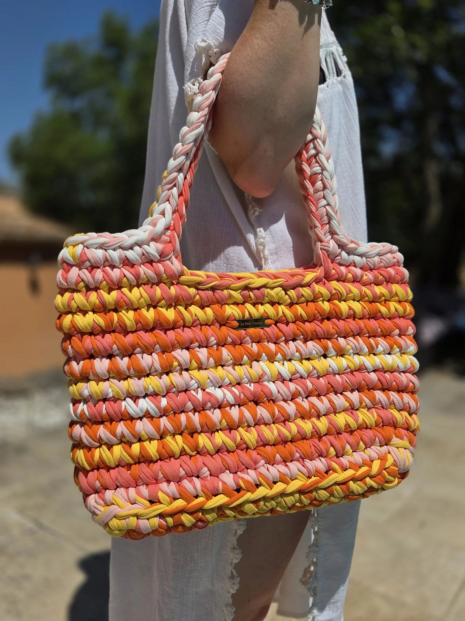 Cabas Siena au crochet, pièce unique Sorbet : rayures orange, corail, pêche, jaune et blanc, porté à la main